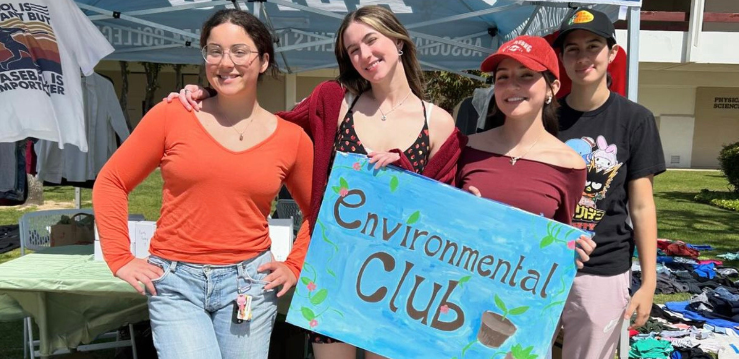 Four Environmental Club members pose together for group photo while holding a sign that says Environmental Club
